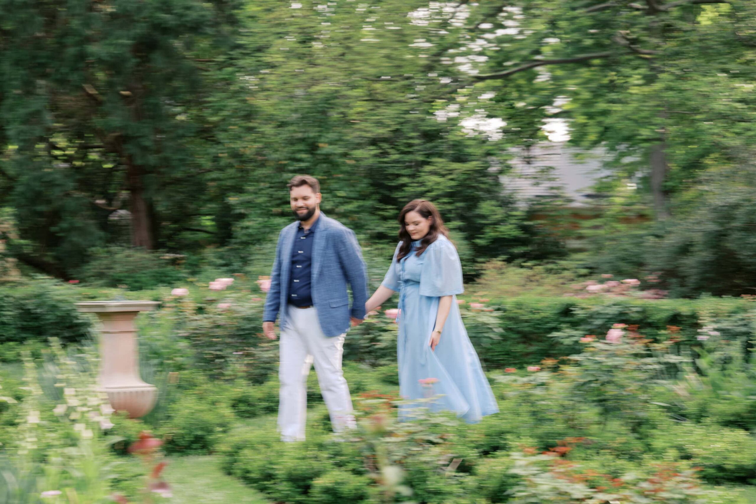Couple walking at Tudor Place, a historic home and garden in Georgetown. The woman is wearing a blue dress and the man is wearing white chinos, brown shoes and a blue jacket.
